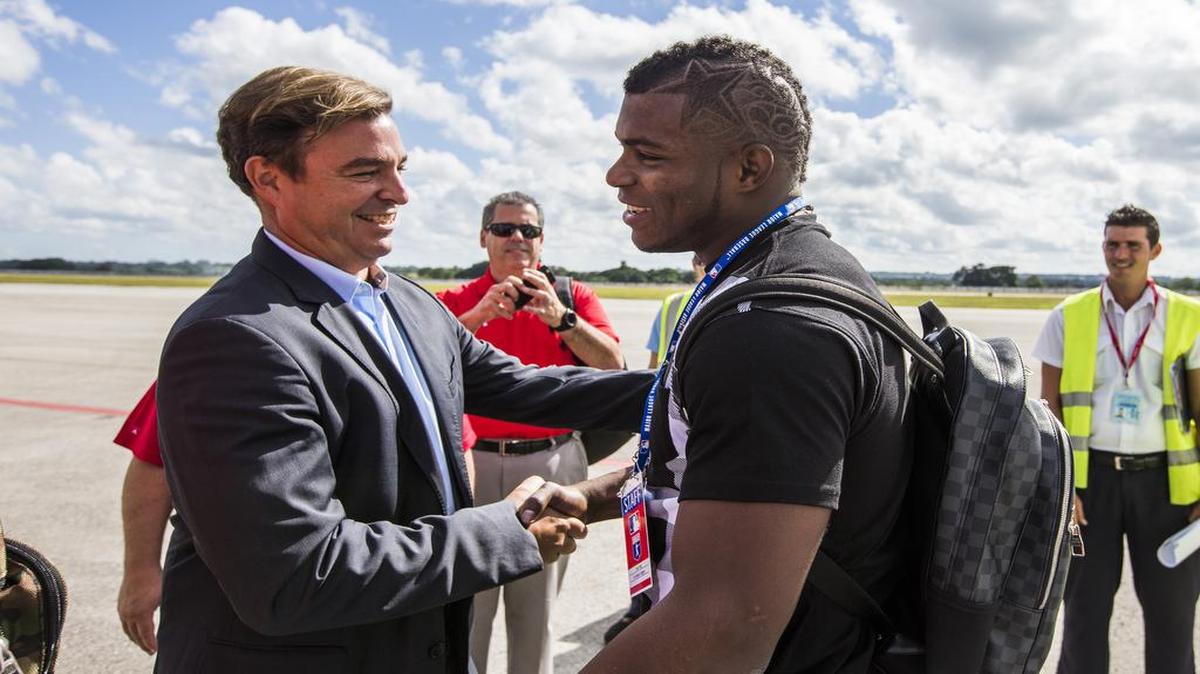 El jardinero de los Dodgers de Los Angeles Yasiel Puig (der.) estrecha la mano de Antonio Castro, hijo de Fidel Castro, vicepresidente de la Federación Internacional de Béisbol  y la principal autoridad del béisbol en la isla.