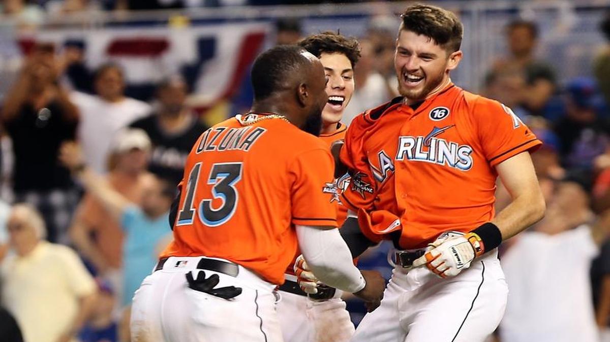 J.T. Riddle (der.) es felicitado por Marcell Ozuna (13) y Christian Yelich luego de haber disparado el jonrón de la victoria de los Marlins sobre los Mets, en el noveno episodio, en el Marlins Park el domingo 16 de abril del 2017.