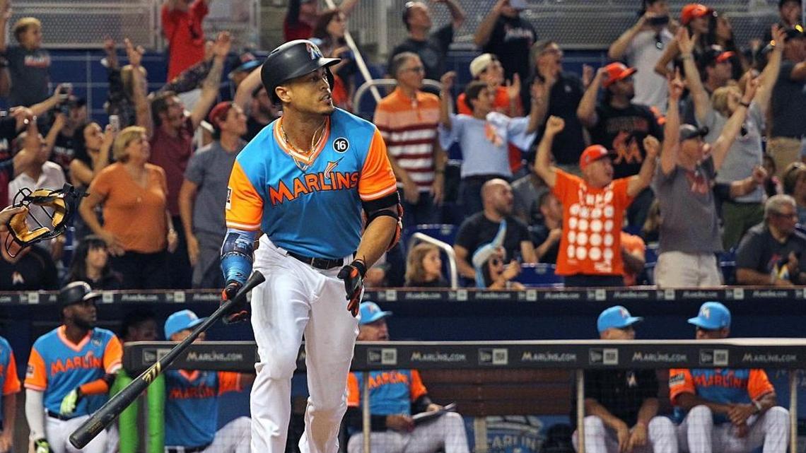 Giancarlo Stanton, de los Marlins, mira el viaje de la pelota para sumar su jonrón número 50, mientras atrás celebran los aficionados, en el juego contra los Padres, el domingo 27 de agosto del 2017 en Miami.