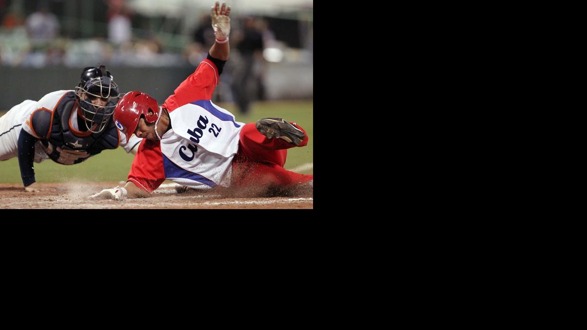 
Yadiel Hernandez se desliza para superar al catcher de Venezuela José Gil y anotar una carrera para la sorprendente Cuba, el sábado en las semifinales.
