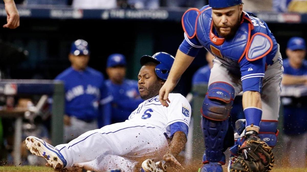 Lorenzo Cain anota para los Reales sin que el catcher de los Azulejos Russell Martin pueda evitarlo, tras un hit de Eric Hosmer, en el octavo inning en el sexto juego de la Serie de Campeonato de la Liga Americana, el viernes 23 de octubre del 2015, en Kansas City, Mo. Con esa carrera los Reales avanzaron a la Serie Mundial.