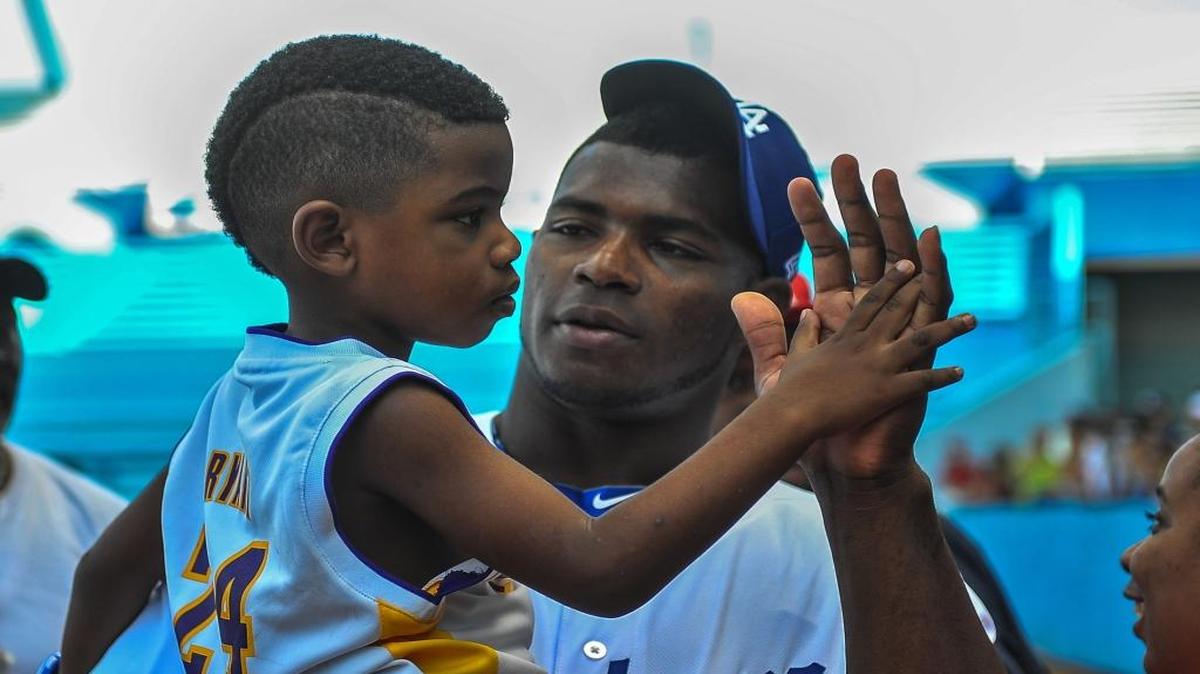 Yasiel Puig carga a su sobrino durante un entrenamiento con niños en el estadio Latinoamericano en La Habana, como parte de la visita de una delegación de Grandes Ligas a Cuba, el 16 de diciembre del 2015.