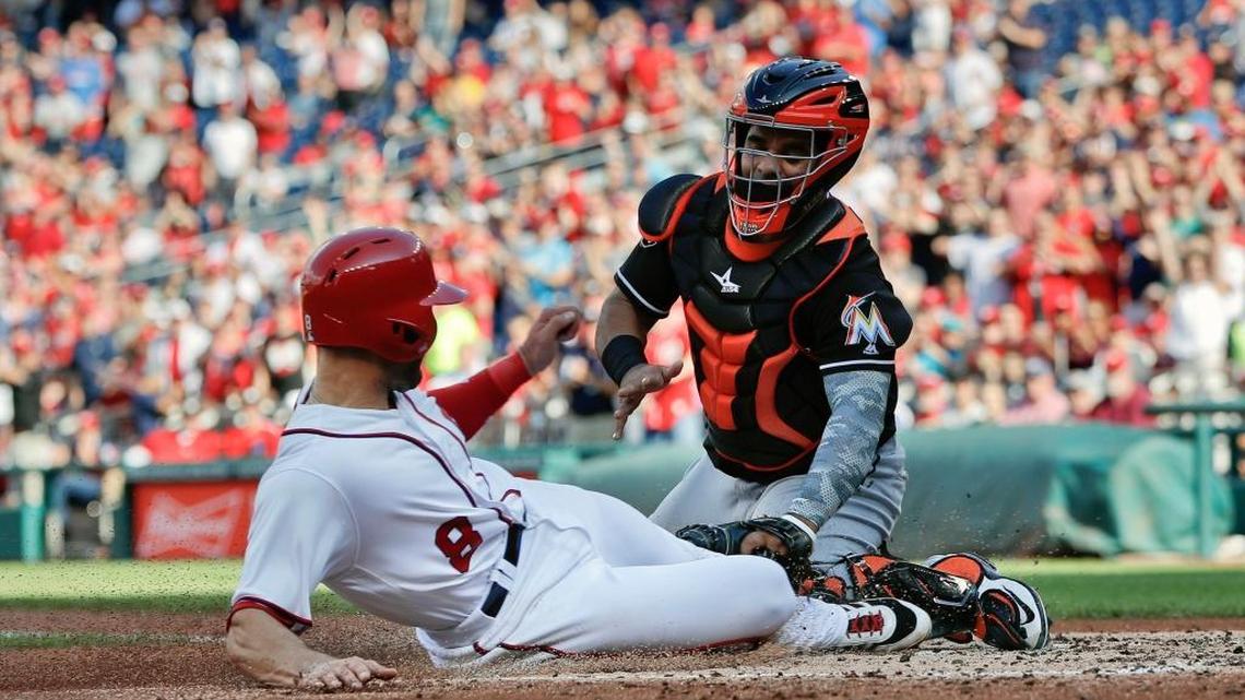 Danny Espinosa (izq.), de los Nacionales, anota ante Tomas Telis, de los Marlins, el domingo.