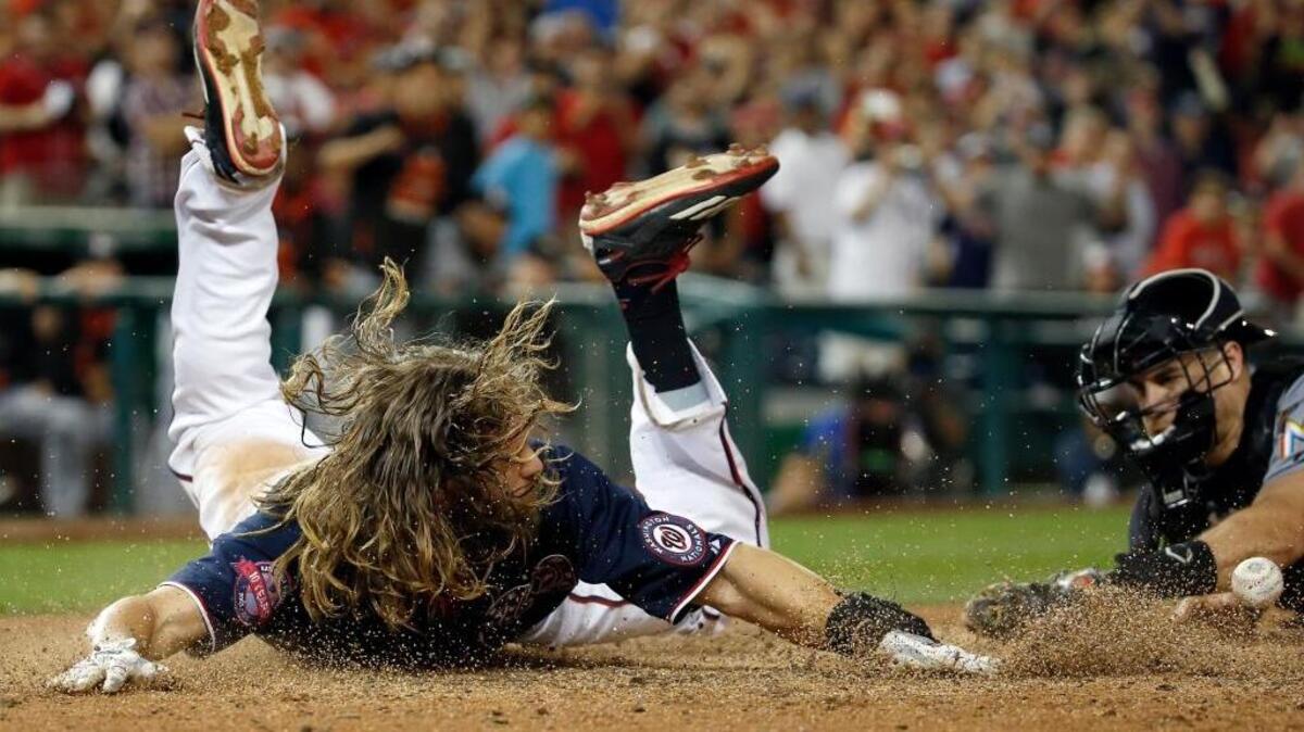 
Jayson Werth, de los Nacionales, anota la carrera de la victoria en un fly de sacrificio de José Lobatón sin que pueda evitarlo en catcher de los Marlins de Miami J.T. Realmuto (der.), en el décimi inning, en el Nationals Park, la noche del viernes 18 de septiembre del 2015, en Washington. Los Nacionales ganaron 5-4.
