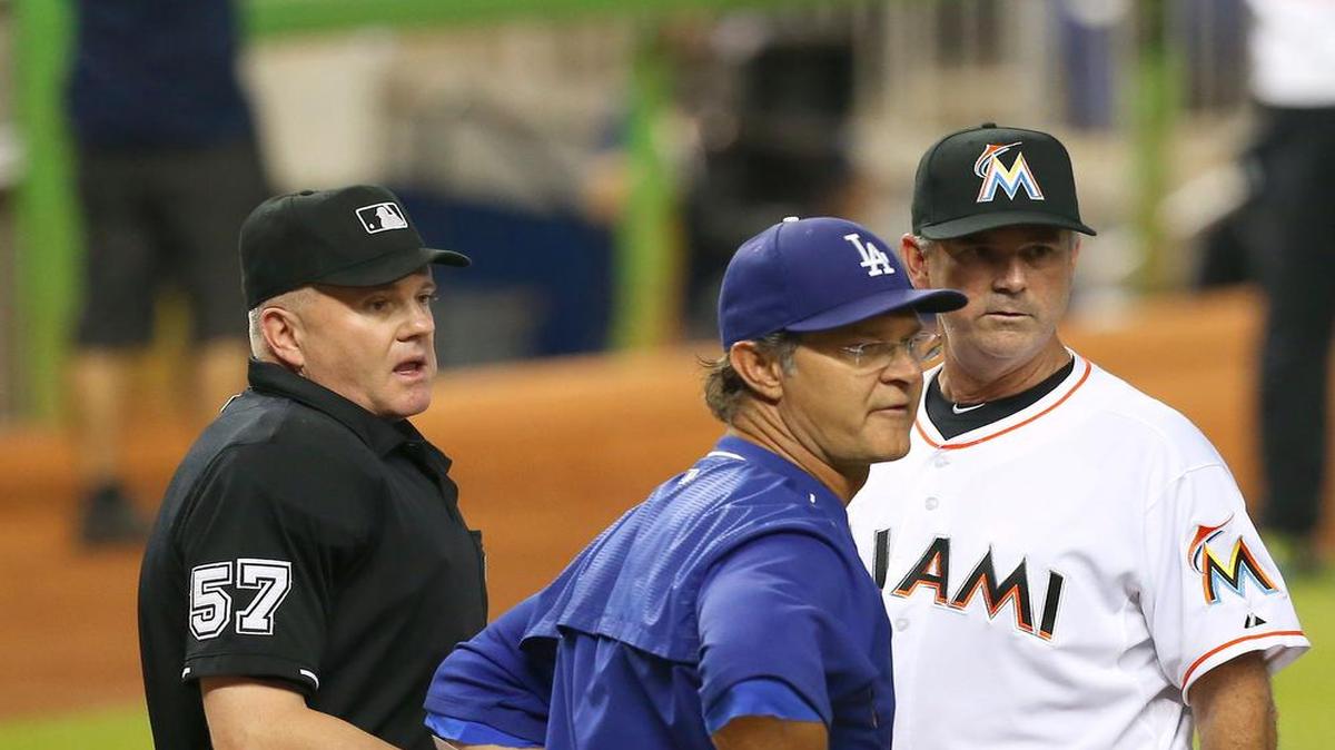 Don Mattingly (centro) y Dan Jennings (der.) discuten con el árbitro de home las reglas antes del comienzo del partido entre los Dodgers y los Marlins, el 26 de junio del 2015 en Miami.