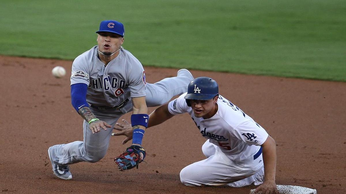 JAVIER BÁEZ de los Cachorros de Chicago (izq.) retorna la bola a la inicial en jugada de doble matanza mientras que Corey Seager de los Dodgers se desliza para evitarlo.