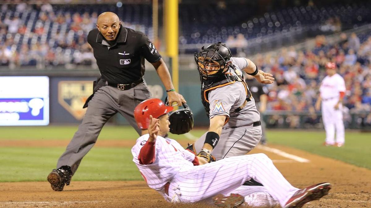 Aaron Altherr anota una carrera por los Filis ante el receptor de los Marlins A.J. Ellis en el partido efectuado el miércoles 13 de septiembre de 2017 en Filadelfia.