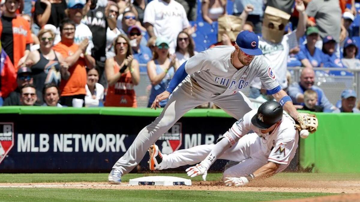 DEREK DIETRICH se desliza quieto en la tercera base evitando a Kris Bryant en la tercera entrada.