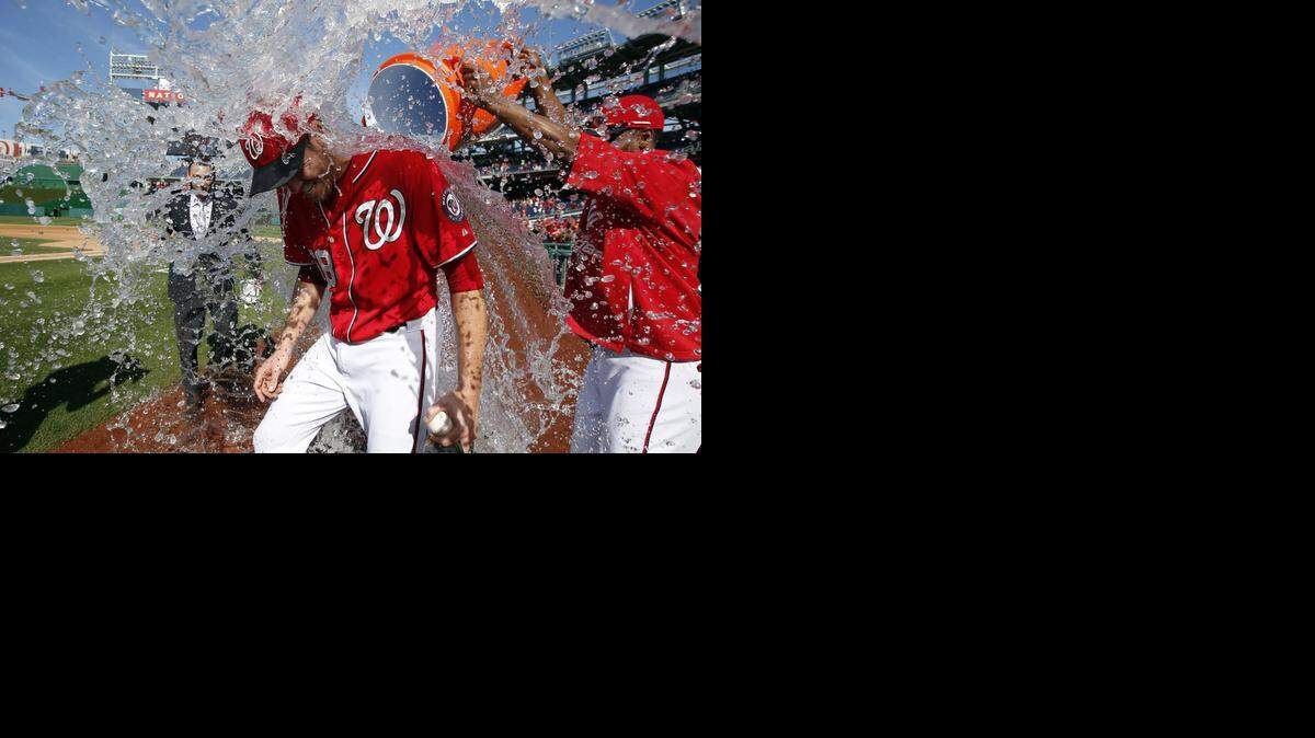 
El pitcher de los Nacionales Doug Fister es bañado por su compañero Michael Taylor luego de haber ganado el primer partido de la jornada doble a los Marlins de Miami, el viernes en Washington.
