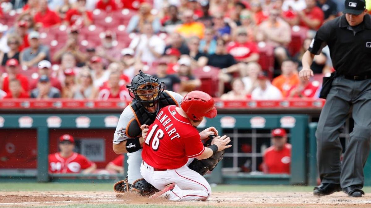 A.J. Ellis, de los Marlins, pone out en el plato a Tucker Barnhart (16), de los Rojos, el domingo en Cincinnati.