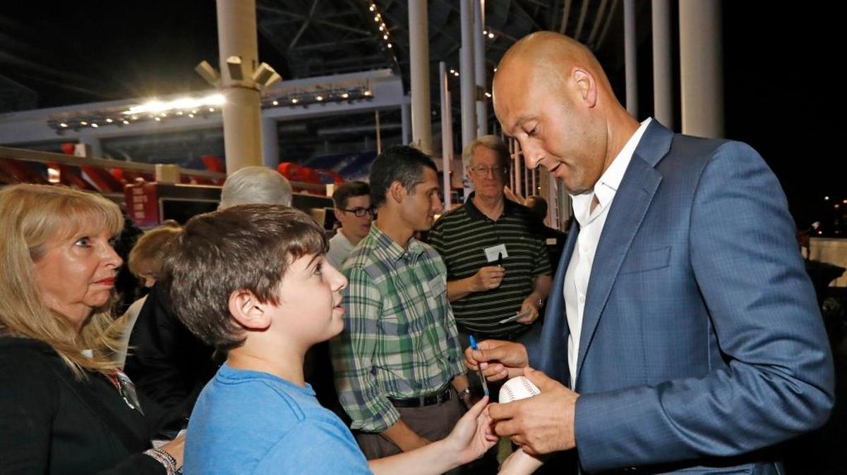 DEREK JETER firma una pelota a un aficionado durante un encuentro con abonados de temporada el 19 de diciembre en el Marlins Park.
