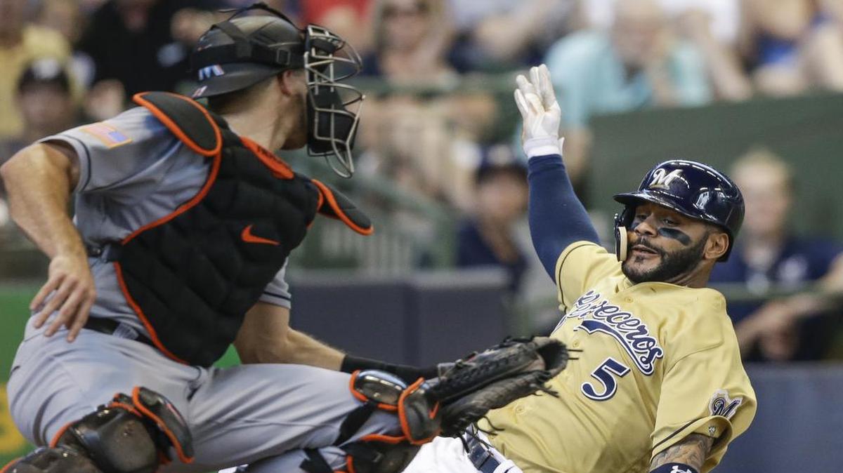 Jonathan Villar, de los Cerveceros, se adelanta a J.T. Realmuto, de los Marlins, y anota, el sábado.