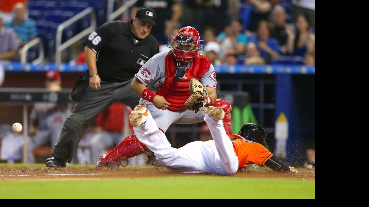 
El receptor de los Rojos Brayan Peña no puede impedir que anote Adeiny Hechavarría, en un doble impulsor de dos carreras de Justin Bour para los Marlins, el domingo 12 de julio del 2015 en Miami.
