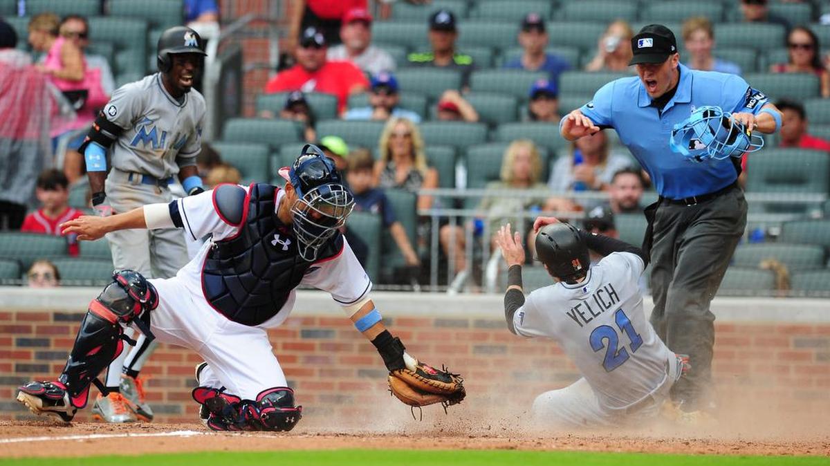 Christian Yelich (21), de los Marlins, llega primero que Kurt Suzuki, de los Bravos, y anota, el domingo.