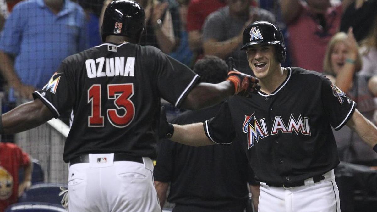 MARCELL OZUNA celebra con J.T. Realmuto (d) tras anotar una carrera contra los Nacionales el 21 de mayo del 2016.