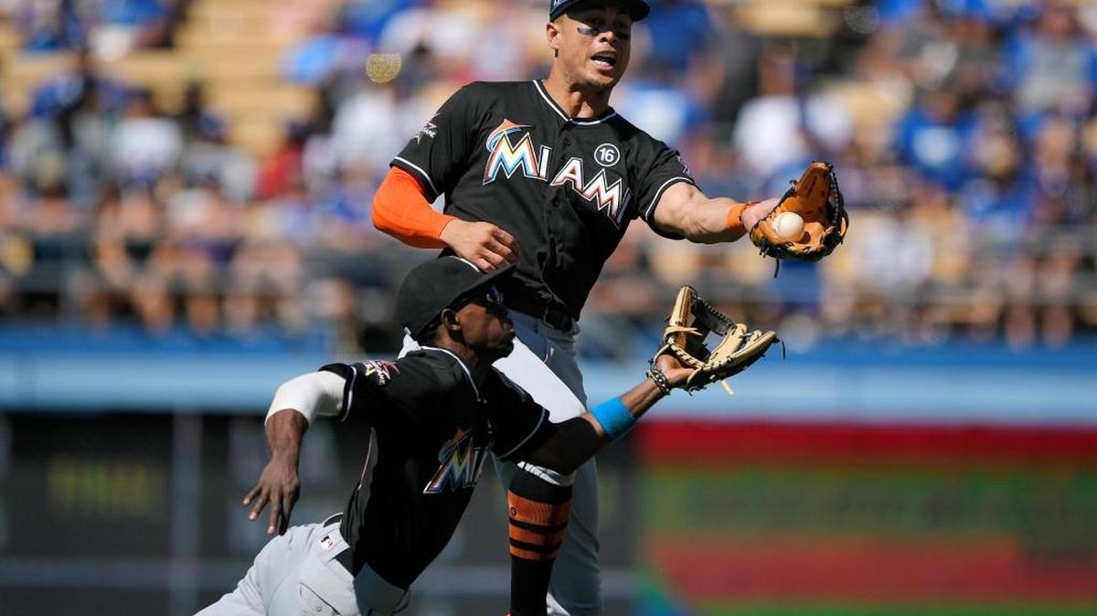 Giancarlo Stanton, de los Marlins, atrapa una pelota luego de un hit de Enrique Hernández, de los Dodgers, mientras Dee Gordon interviene para ayudar en el octavo inning, el domingo 21 de mayo del 2017, en Los Ángeles.