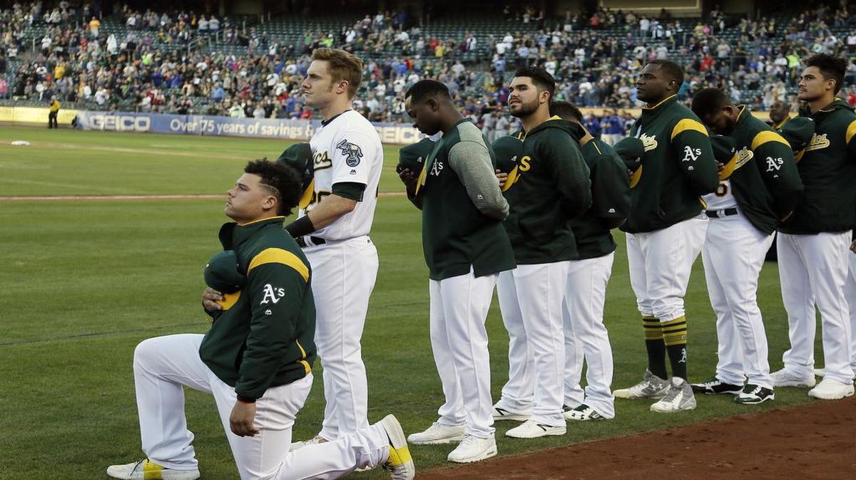 Bruce Maxwell, de los Atléticos de Oakland se arrodilla durante el himno nacional de los Estados Unidos en un juego contra los Rangers de Texas el sábado 23 de septiembre de 2017.