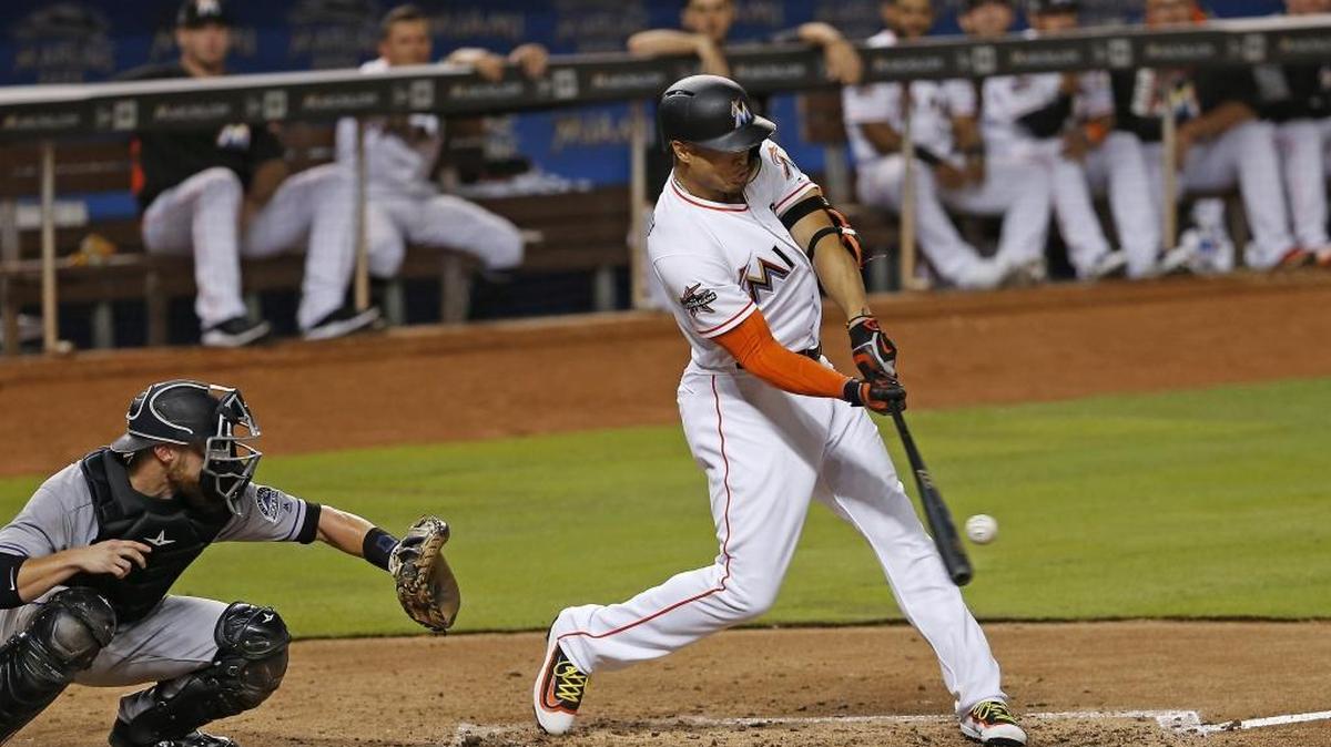 Giancarlo Stanton, de los Marlins, dispara un sencillo en el tercer inning contra los Rockies, en el Marlins Park la noche del viernes 11 de agosto del 2017 en Miami.