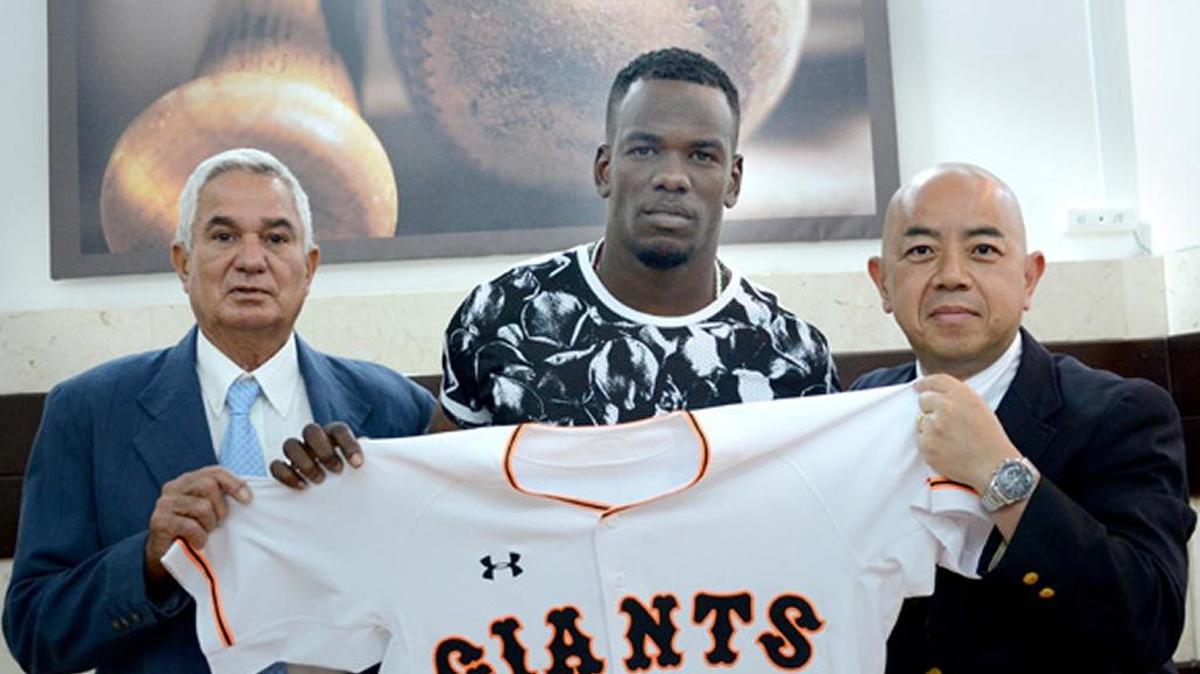 KATSUTOSHI TSUZAKI (D), Director de Relaciones Internacionales los Gigantes de Yomiuri, junto a Higinio Vélez (I), Presidente de la Federación Cubana de Béisbol, y el pelotero cubano José Adolis García (C) durante la firma del contrato.