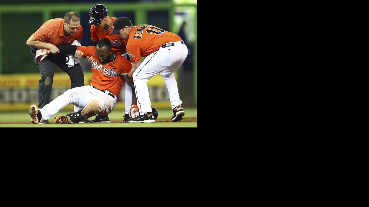 
El mánager de los Marlins Mike Redmond (11), el coach de tercera base Brett Butler (centro) y un entrenador del equipo tratan de levantar a Marcell Ozuna, tras lesionarse en una jugada en segunda base el domingo 21 de septiembre.


