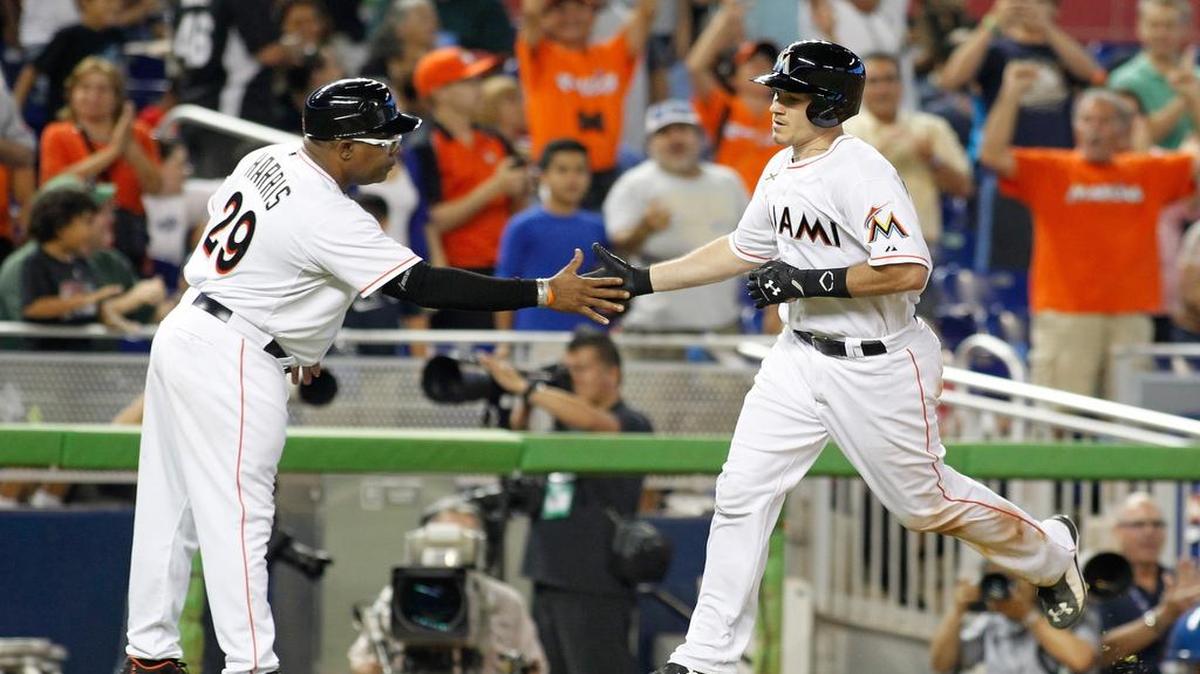 
 J.T. Realmuto (der.) es saludado por el coach de tercera base Lenny Harris tras pegar un jonrón con bases llenas por los Marlins en el sexto inning, el miércoles 12 de agosto del 2015 en Miami.

