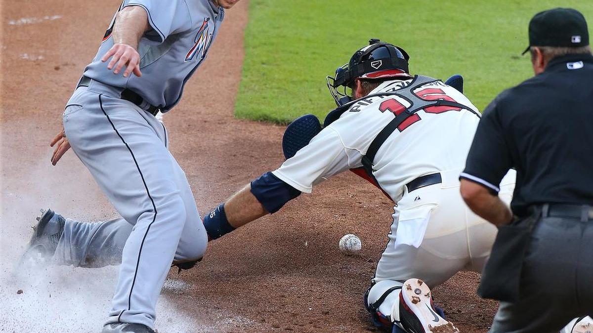 
J.T. Realmuto anota para los Marlins luego de un toque de pelota de Brad Hand contra los Bravos, el domingo.
