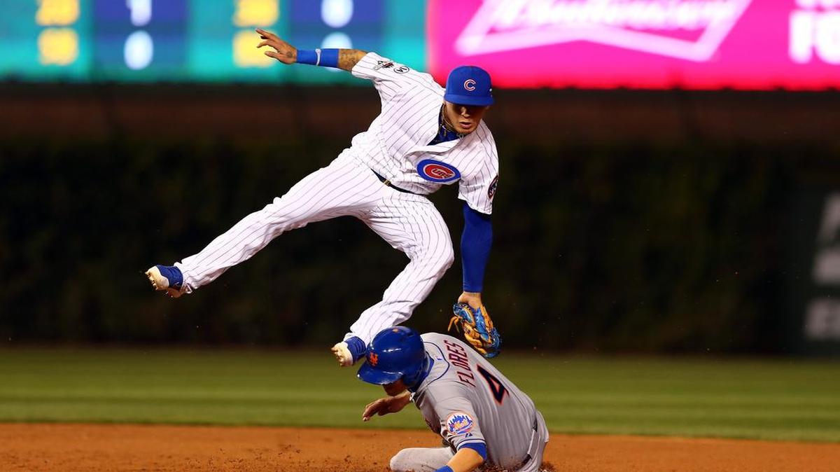 El torpedero de los Cachorros Javier Báez (izq.) trata de poner out en segunda base al corredor de los Mets Wilmer Flores, en el cuarto partido de la Serie de Campeonato de la Liga Nacional, el 21 de octubre del 2015, en Chicago.