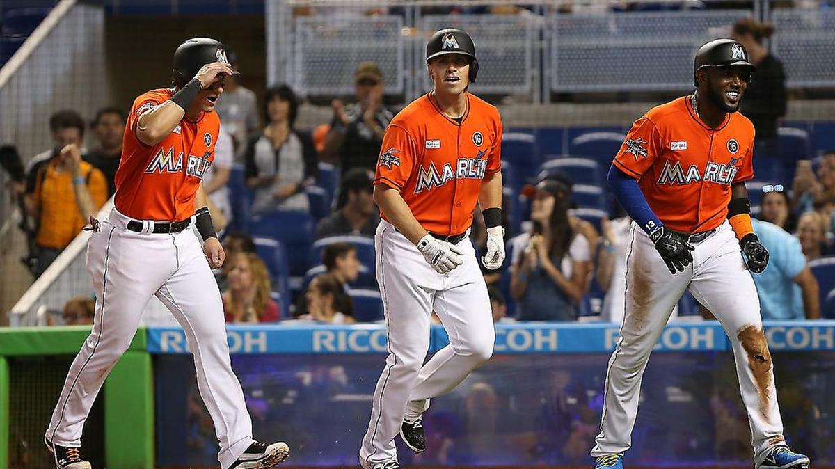 Tyler Moore (centro), de los Marlins, es felicitado por Derek Dietrich (izq.) y Marcell Ozuna luego de disparar un jonrón de tres carreras en el segundo inning contra los Diamondbacks, el domingo 4 de junio del 2017.