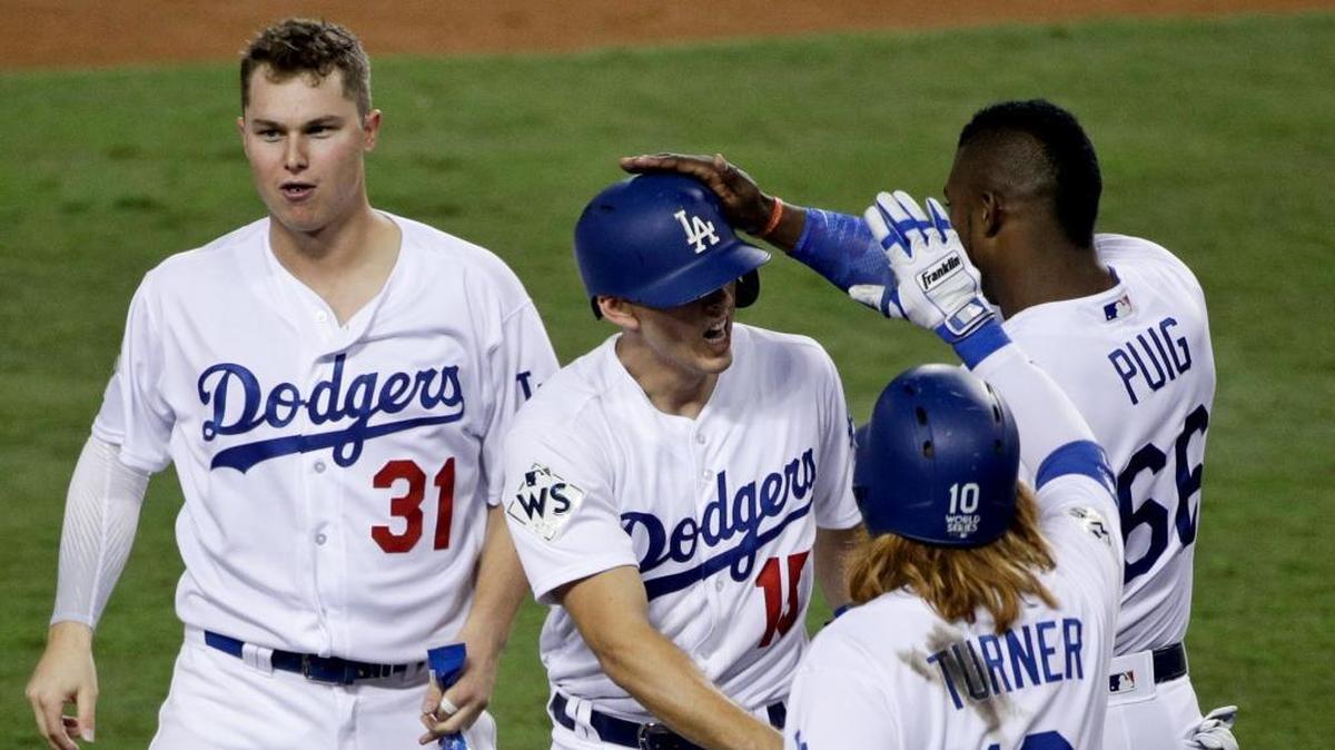 El receptor de los Dodgers Austin Barnes (centro) celebra tras anotar la primera carrera de su equipo en el sexto episodio ante los Astros, en el sexto juego de la Serie Mundial, celebrado el 31 de octubre del 2017 en Los Ángeles.