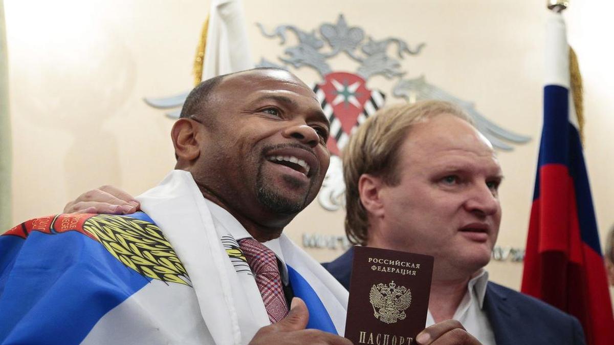 El boxeador estadounidense Roy Jones Jr. (izq.) muestra su pasaporte ruso junto a su patrocinador Vladimir Khryunov en la oficina de inmigración de Moscú, Rusia, el 27 de octubre de 2015.