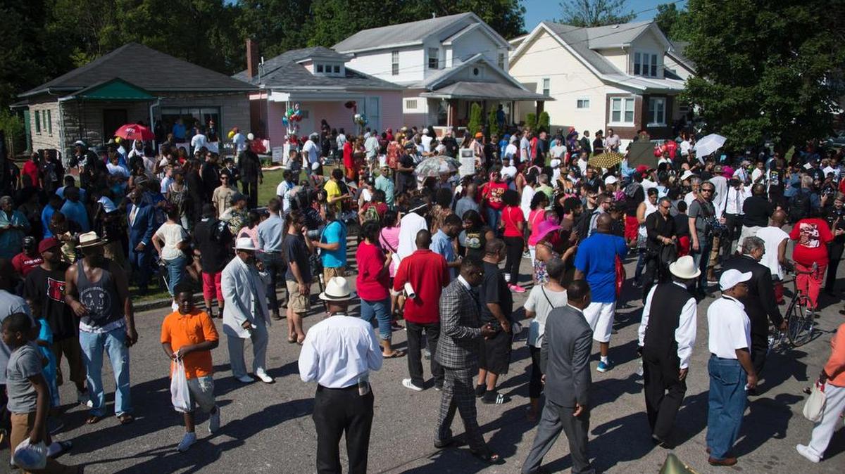 Cientos de personas se reúnen fuera de la casa de la infancia de la leyenda del boxeo Muhammad Ali, donde dolientes esperan para presentar sus respetos durante una procesión funeral el 10 de junio de 2016 en Louisville, Kentucky.