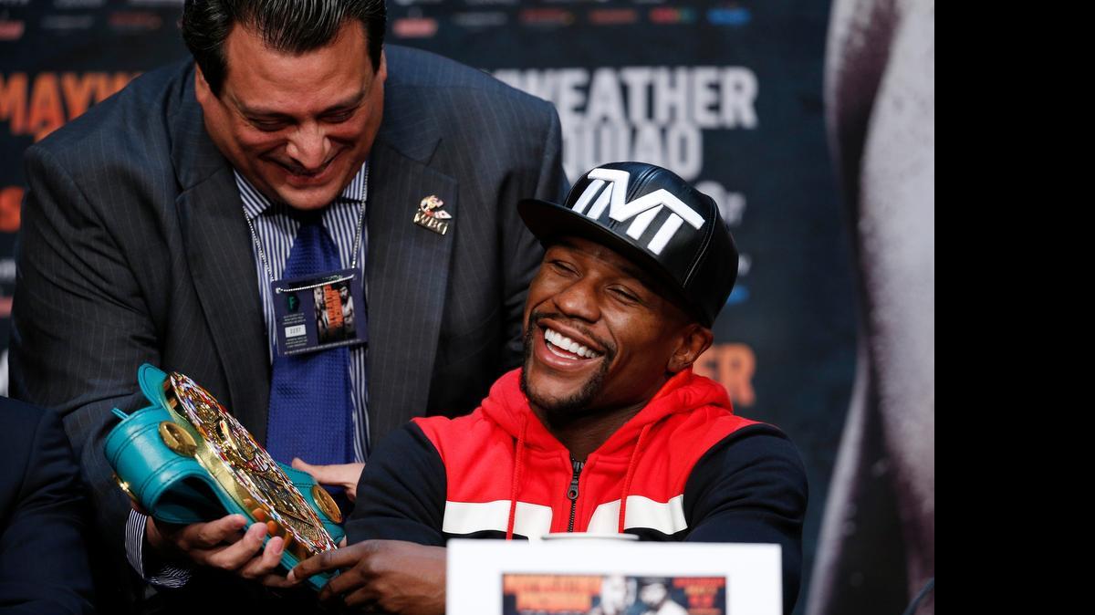 
El presidente del Consejo Mundial de Boxeo Mauricio Sulaimán (izq.) le muestra a Floyd Mayweather Jr. el cinturón que posteriormente el púgil estadounidense se llevó tras vencer a Manny Pacquiao, en una conferencia de prensa el 29 de abril del 2015.
