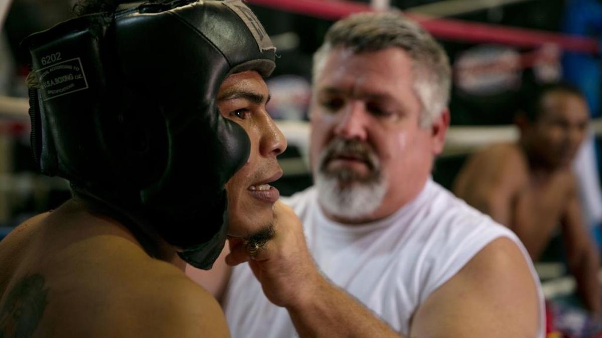 OSMIRI FERNANDEZ ajusta el protector de cabeza de Walter Castillo antes de iniciar un sparring el 26 de septiembre del 2017.