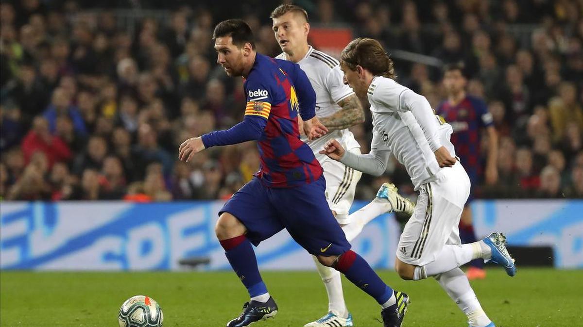 Lionel Messi, del Barcelona (izq.), corre con el balón ante la marca de los jugadores del Real Madrid Luka Modric (der.) y Toni Kroos, el pasado 18 de diciembre. El Barça se enfrenta este sábado al Espayol y el Madrid al Getafe, en dos duelos regionales.