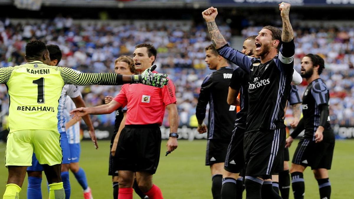 El defensa del Madrid Sergio Ramos (d) alza los brazos festejando el segundo gol marcado por el delantero francés Karim Benzema ante el Málaga CF, durante el partido de la última jornada de Liga en Primera División que se jugó el dominfo el estadio de La Rosaleda, en Málaga. EFE/Jorge Zapata