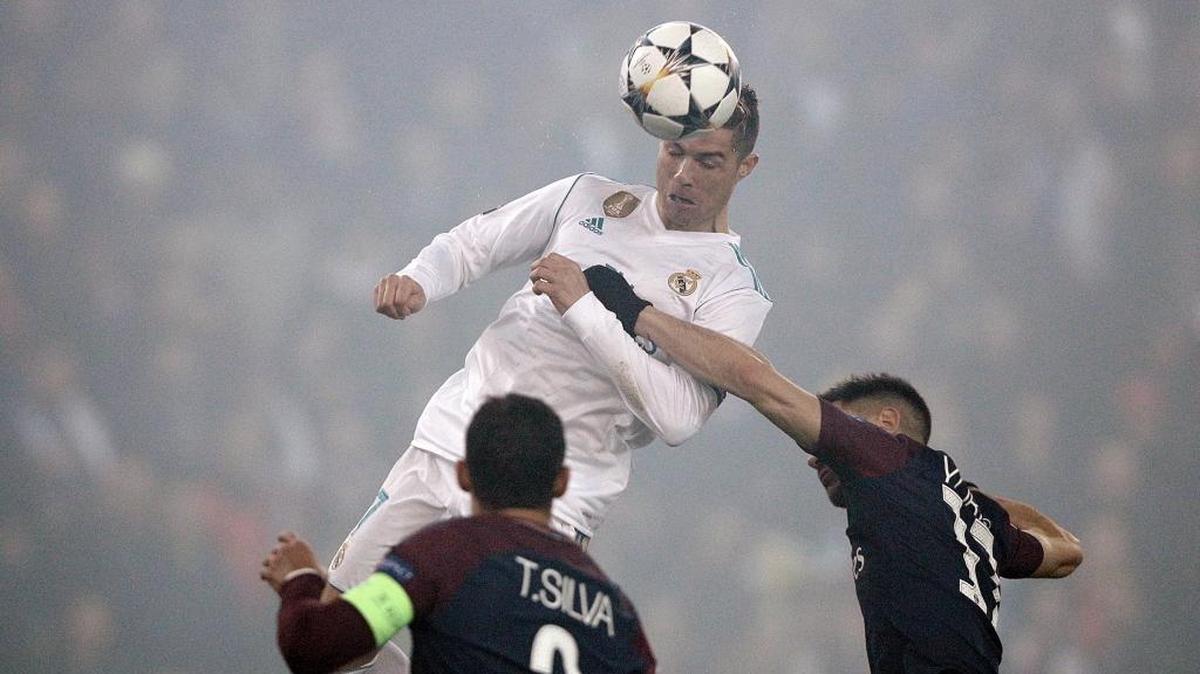 Cristiano Ronaldo (c) de Real Madrid remata a puerta y anota de cabeza el 1-0 ante el Paris Saint-Germain en el partido de vuelta de los octavos de final de la Liga de Campeones UEFA.