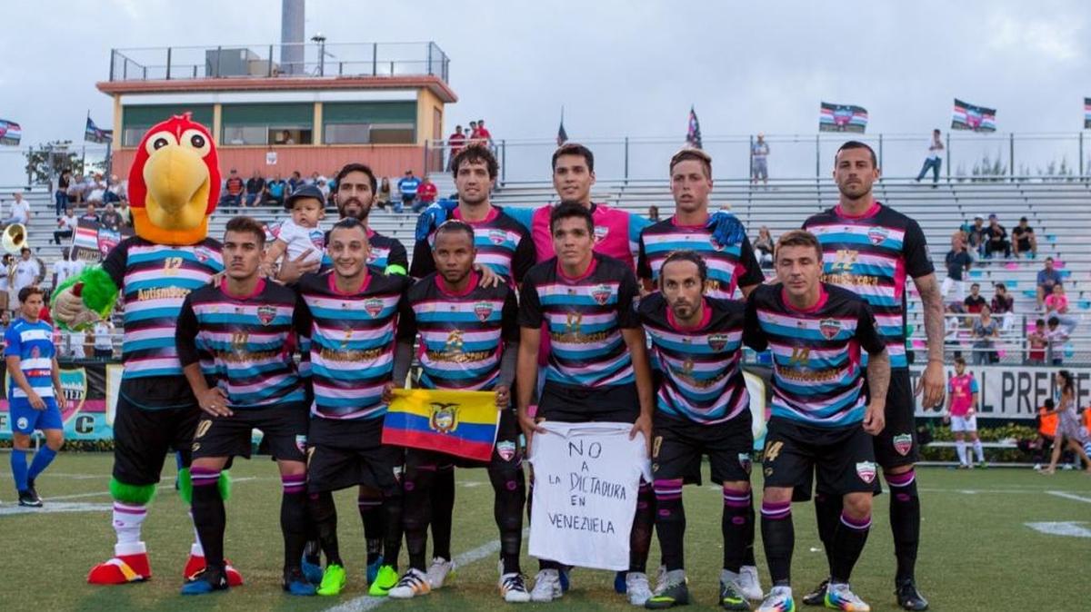 El Miami United FC se forma para el partido contra el Boca Raton FC, por el campeonato de la Sunshine Conference de la National Premier Soccer League, el domingo 30 de abril del 2017 en el Ted Hendricks Stadium en Hialeah, Florida. El capitán Ezequiel Tejera tiene en brazos a su hijo Matías; Max Rodríguez luce la bandera ecuatoriana; y el exseleccionado de la vinotinto Juan Fuenmayor muestra un mensaje contra la dictadura de Venezuela. También aparece el resto del equipo abridor del domingo y Bazuca, la mascota del equipo.