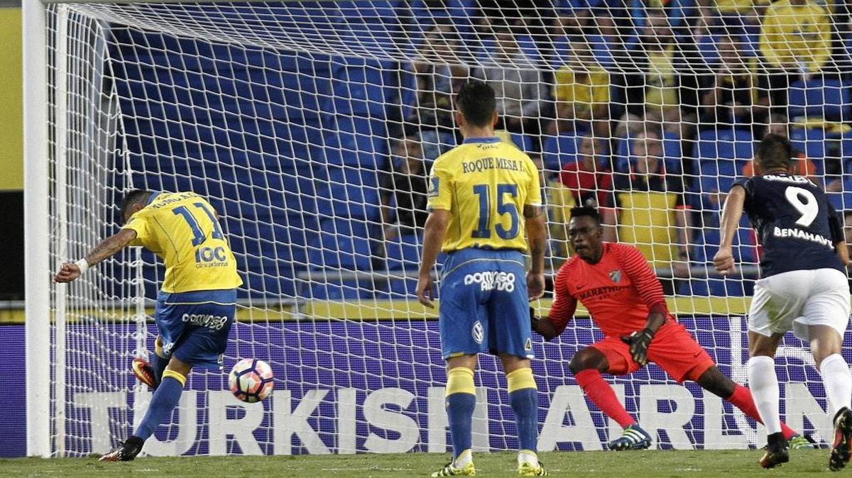El delantero de la U.D. Las Palmas Momo (i) bate al portero camerunés del Málaga Carlos Kameni (2d), el sábado en el estadio de Gran Canaria.