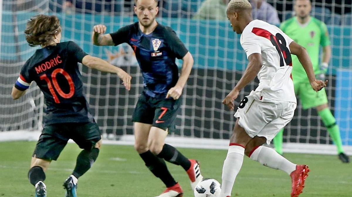 Andre Carrillo, de Perú (der.) trata de escapar de la marca de los volantes de Croacia  Ivan Rakitic y Luka Modric (izq.) el 23 de marzo en un amistoso en el Hard Rock Stadium .