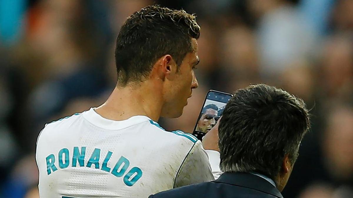 El delantero del Real Madrid Cristiano Ronaldo se mira en el teléfono del médico la herida al lado del ojo al final del partido contra el Deportivo la Coruña.