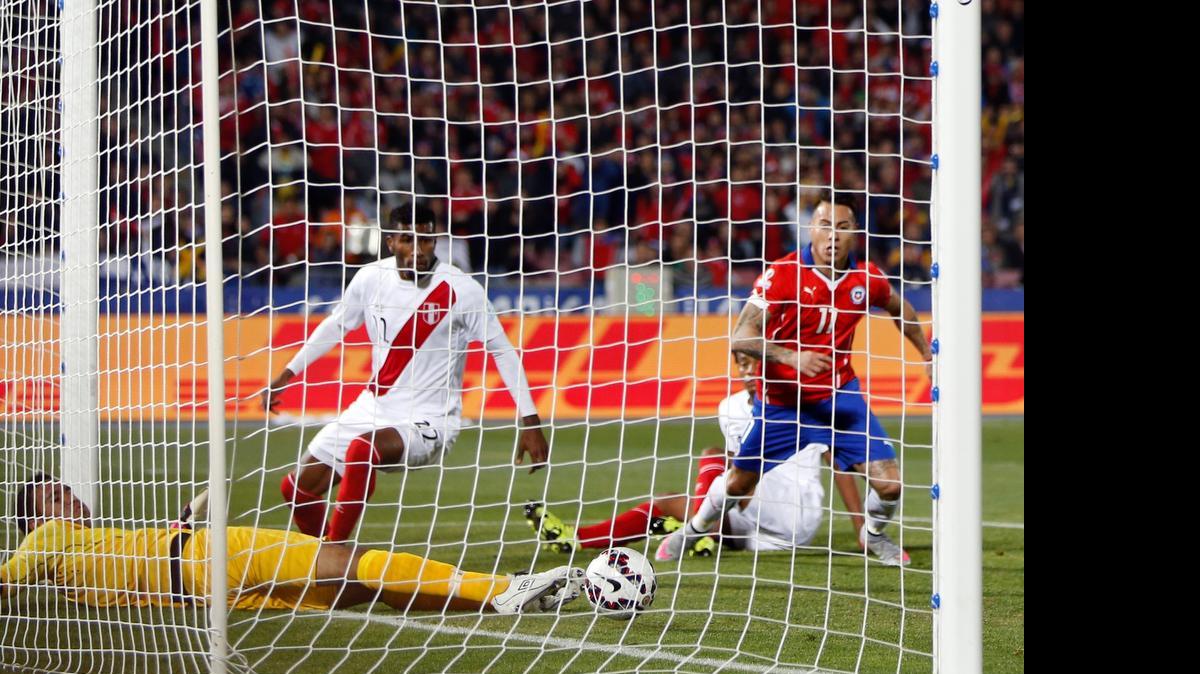 
El arquero de Perú Pedro Gallese (izq.) no puede evitar el disparo Eduardo Vargas (der.) para poner en ventaja a Chile, en las semifinales de la Copa América en el Estadio Nacional de Santiago de Chile, el lunes 29 de junio del 2015.
