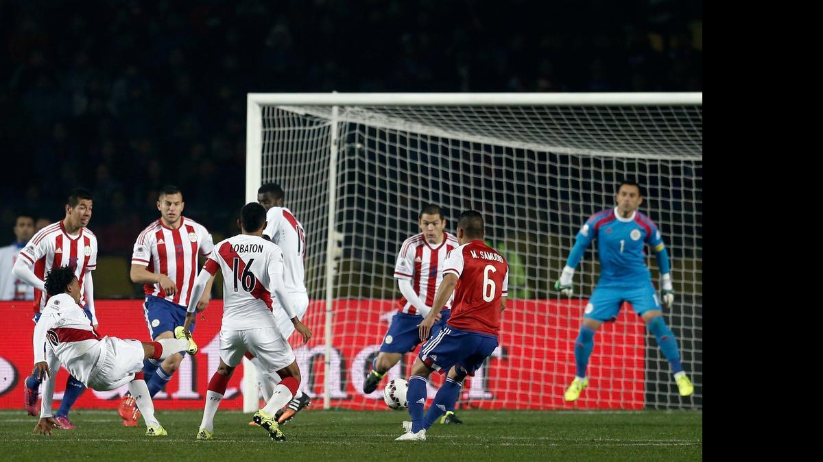 
André Carrillo (izq.), cayéndose, dispara para anotar y poner en ventaja a Perú contra Paraguay en la Copa América, en el estadio Ester Roa Rebolledo en Concepción, Chile, el viernes 3 de julio del 2015.
