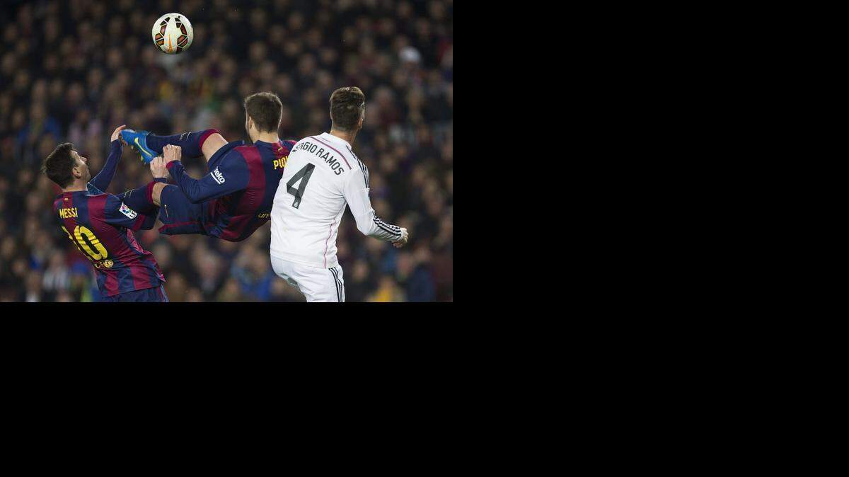 El defensa de Barcelona, Gerard Piqué (centro) intenta rematar ante su compañero, el argentino Leo Messi (izq.) y Sergio Ramos, del Real Madrid, durante el partido entre ambos equipos el 22 de marzo del 2015 en el estadio del Camp Nou, Barcelona. 
