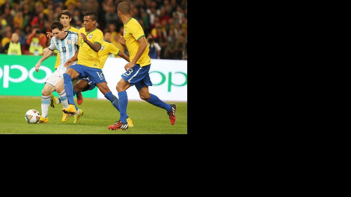 
Lionel Messi de Argentina trata de evadir la marca de Luiz Gustavo (centro), el sábado en Pekín.
