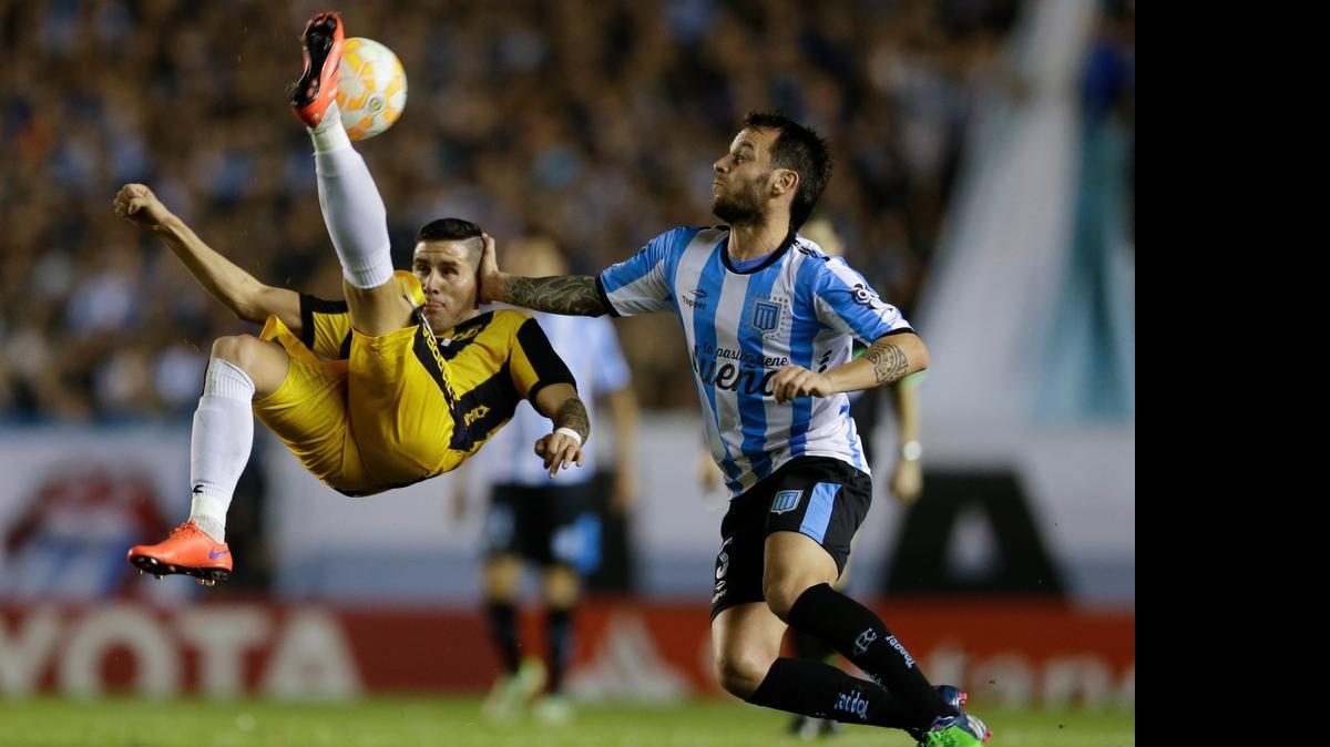 
El mediocampista de Guaraní, Jorge Mendoza (izq.), despeja un balón de chilena frente al acecho del volante de Racing Club, Ezequiel Videla, durante el partido de cuartos de final de la Copa Libertadores. 
