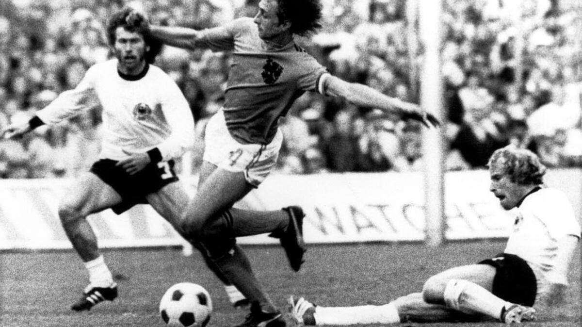 Fotografía de archivo tomada el 7 de julio de 1974 que muestra a los defensas alemanes Paul Breitner (i) y Berti Vogts (d) que luchan por el balón con el holandés Johan Cruyff (c) durante la final de la Copa del Mundo de 1974 entre Alemania y Holanda en Múnich (Alemania). El exfutbolista holandés Johan Cruyff ha fallecido hoy en Barcelona a los 68 años de edad, tras meses de lucha contra el cáncer, según ha confirmado su familia en su cuenta oficial de Twitter.