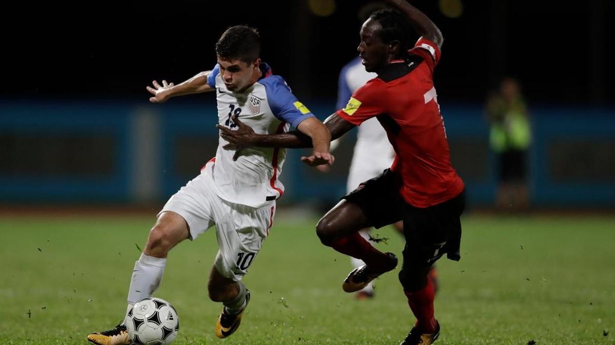 Christian Pulisic, de Estados Unidos, se lleva la pelota marcado por Nathan Lewis, de TT, el martes en Couva, Trinidad.