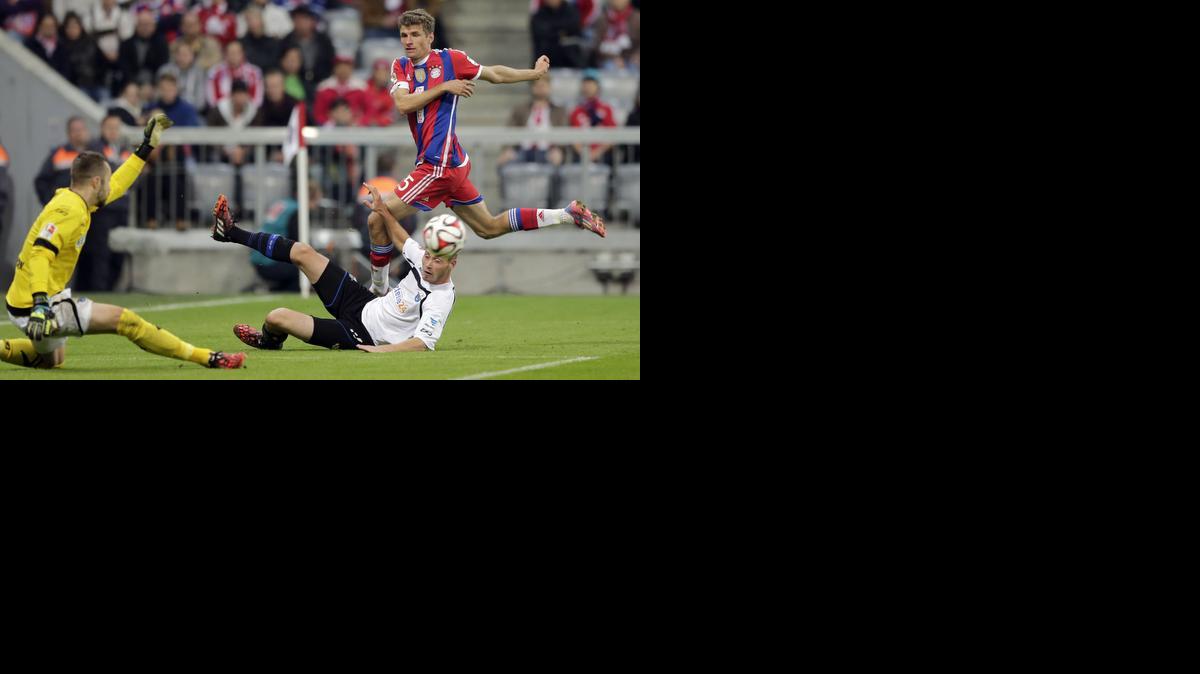 
El jugador del Bayern de Munich Thomas Muller (der.) dispara a puerta ante Christian Strohdiek y del portero del Paderborn Lukas Kruse (izq.).


