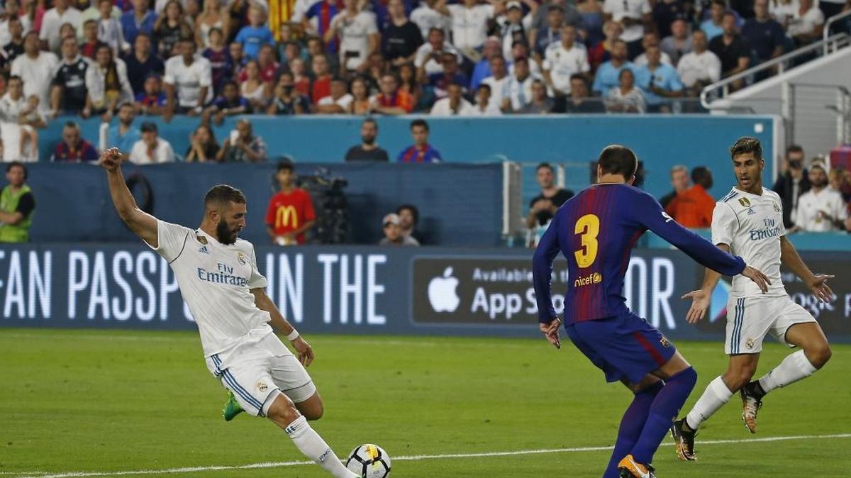 Karim Benzema, del Real Madrid (izq.), dispara a puerta ante la marca de Gerald Piqué, del Barcelona, el 29 de julio en Miami.