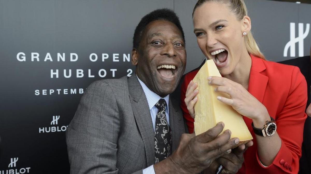 El ex jugador brasileño Pelé y la modelo israelí Bar Refaeli posan con una pieza de queso gruyere durante la ceremonia de inauguración de una nueva planta de la marca de relojes de lujo Hublot en Nyon, el 29 de septiembre de 2015.